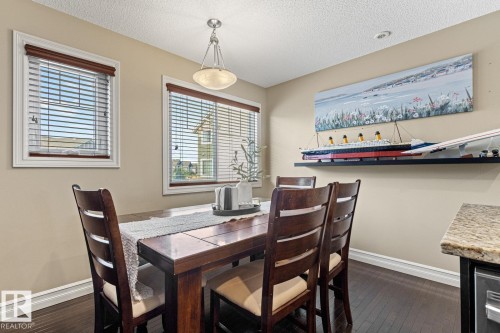 Dining area featuring dark wood-finish flooring, two windows with white trim, and a built-in ceiling light fixture - 5319 3 Avenue Sw, Edmonton, AB 
