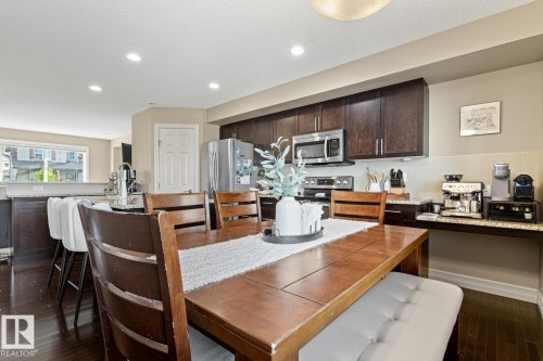 Kitchen featuring dark wood-finish cabinetry, stainless steel appliances, and a light-toned backsplash - 5319 3 Avenue Sw, Edmonton, AB 