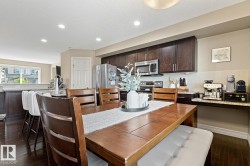 Kitchen featuring dark wood-finish cabinetry, stainless steel appliances, and a light-toned backsplash - 