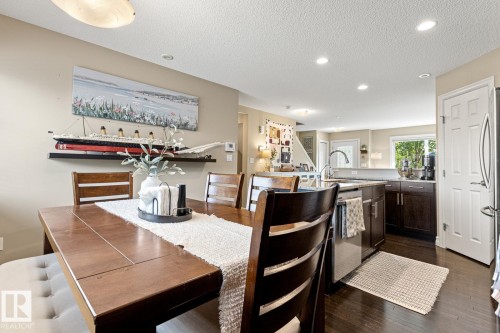 Hardwood flooring, recessed ceiling lighting, kitchen island with integrated sink, dark wood-finish cabinetry, and light-toned walls - 5319 3 Avenue Sw, Edmonton, AB 