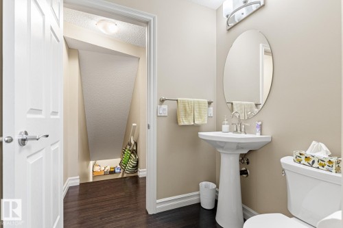 Pedestal sink with chrome faucet, oval mirror, and overhead vanity lighting - 5319 3 Avenue Sw, Edmonton, AB 