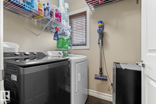 Laundry area featuring a window with blinds, wall-mounted shelving, and wood-finish flooring - 5319 3 Avenue Sw, Edmonton, AB 