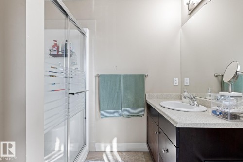 Shower with sliding frosted glass doors, a vanity with an integrated sink, a chrome faucet, and a large wall-mounted mirror - 5319 3 Avenue Sw, Edmonton, AB 