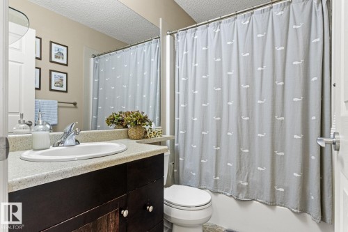 Bathroom with an integrated sink vanity, a dark wood-finish cabinet, and a full-width wall mirror - 5319 3 Avenue Sw, Edmonton, AB 