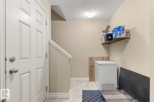 Panel door with brushed nickel hardware, tiled flooring, built-in wall shelf, and textured ceiling - 5319 3 Avenue Sw, Edmonton, AB 