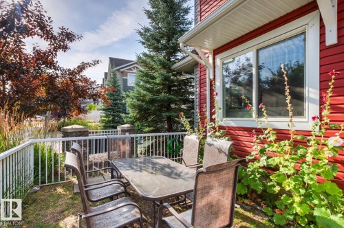 Private exterior patio featuring a white railing, stone-capped pillars, and established landscaping - 5319 3 Avenue Sw, Edmonton, AB 