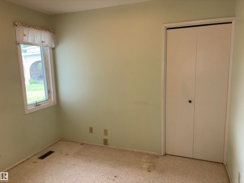 Window with exterior landscaping visible, light-colored walls, and a bi-fold closet door - 4027 74 Street Nw, Edmonton, AB 