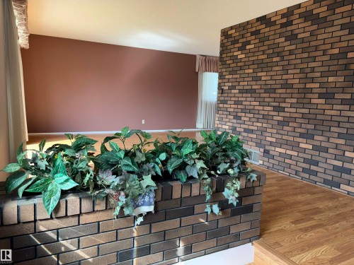 Brick accent wall and planter with wood-finish flooring - 4027 74 Street Nw, Edmonton, AB 