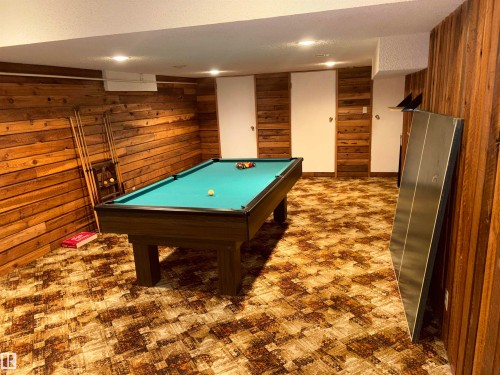 Recreation room featuring wood-paneled walls, recessed lighting, and a patterned carpet - 4027 74 Street Nw, Edmonton, AB 