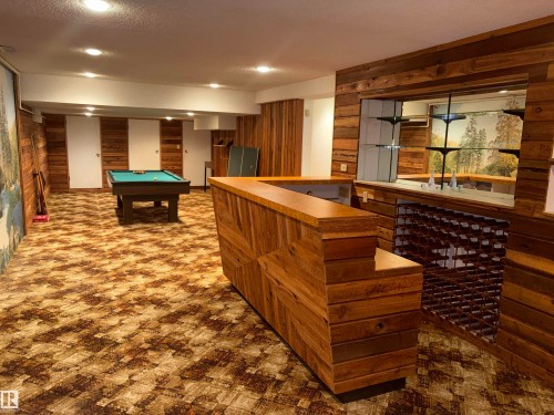 Recreational room featuring wood-paneled walls, a built-in wet bar with shelving, a built-in wine rack, and recessed lighting - 4027 74 Street Nw, Edmonton, AB 