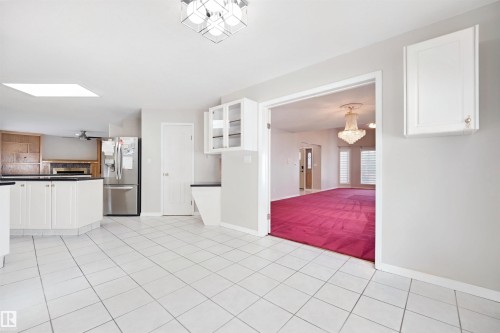 Kitchen featuring white tile flooring, white cabinetry, dark countertops, and a skylight - 5107 17 Avenue Nw, Edmonton, AB 