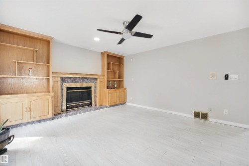 Recessed lighting, light wood-finish flooring, built-in shelving, stone fireplace surround, and ceiling fan - 5107 17 Avenue Nw, Edmonton, AB 