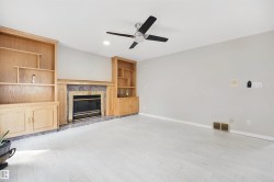Recessed lighting, light wood-finish flooring, built-in shelving, stone fireplace surround, and ceiling fan - 