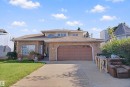 Brick exterior with an integrated two-car garage, concrete driveway, and established landscaping - 5107 17 Avenue Nw, Edmonton, AB 