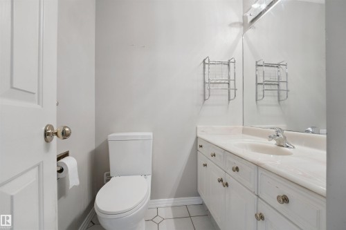 White vanity with a built-in sink, chrome fixtures, and a large wall mirror - 5107 17 Avenue Nw, Edmonton, AB 