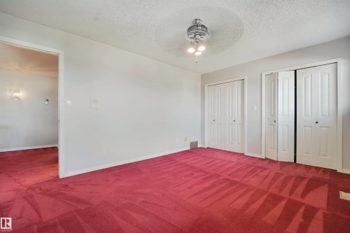 Room featuring two sets of bi-fold closet doors, wall-to-wall carpeting, and a ceiling-mounted light fixture - 5107 17 Avenue Nw, Edmonton, AB 