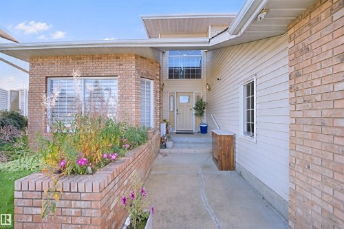 Brick and siding exterior with a concrete walkway, featuring a planter box, bay windows, and a transom window above the entry - 5107 17 Avenue Nw, Edmonton, AB 