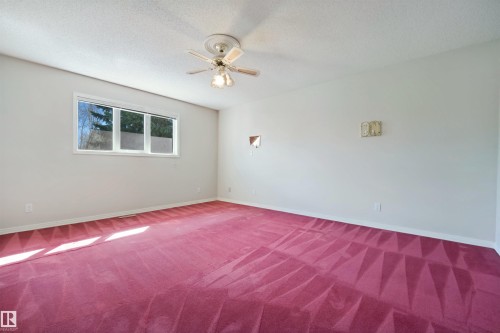 Expansive room featuring a ceiling fan, wall-mounted light fixtures, and a multi-pane window - 5107 17 Avenue Nw, Edmonton, AB 