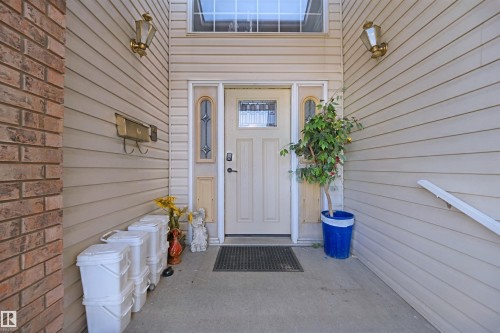 Entryway featuring brick and siding exterior, decorative wall sconces, and a transom window - 5107 17 Avenue Nw, Edmonton, AB 