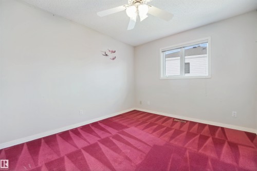 Interior space featuring a ceiling fan with integrated lighting, a double-pane window, and patterned carpet flooring - 5107 17 Avenue Nw, Edmonton, AB 
