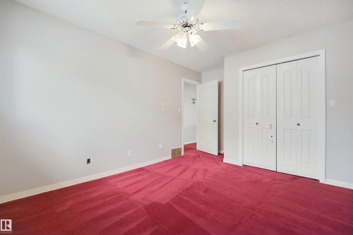 Red carpeting, white bi-fold closet doors, white ceiling fan with integrated lighting, white interior door, and white trim - 5107 17 Avenue Nw, Edmonton, AB 
