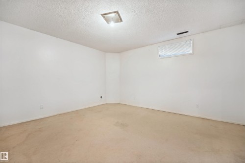 Neutral wall finishes with a textured ceiling, a flush-mount ceiling light fixture, and a window with blinds - 5107 17 Avenue Nw, Edmonton, AB 