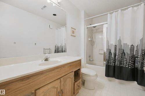Bathroom featuring a wood-finish vanity with a single basin sink and a white countertop - 5107 17 Avenue Nw, Edmonton, AB 