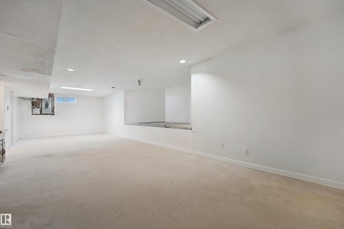 Recessed lighting illuminates a spacious carpeted area with white walls - 5107 17 Avenue Nw, Edmonton, AB 