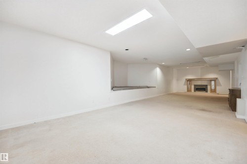 Spacious room with white carpeting, recessed lighting, and a built-in fireplace with a wood mantle - 5107 17 Avenue Nw, Edmonton, AB 