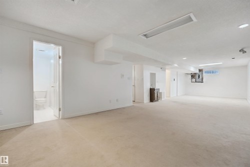 Spacious lower level featuring light-toned carpeting, recessed lighting, and a built-in wet bar with dark-finish cabinetry - 5107 17 Avenue Nw, Edmonton, AB 