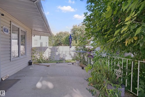 Covered outdoor patio with concrete flooring, framed by decorative metal railing - 5107 17 Avenue Nw, Edmonton, AB 