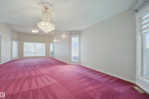 Spacious room featuring multiple large windows, a crystal chandelier, recessed lighting, and a ceiling fan - 5107 17 Avenue Nw, Edmonton, AB 