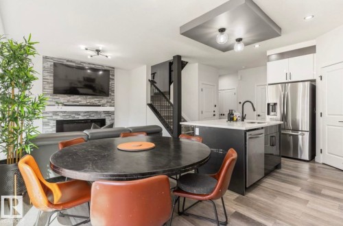 Open-concept living area featuring a stone-clad fireplace and wood-finish flooring - 19703 29 Avenue Nw, Edmonton, AB 