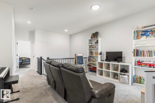 Loft area featuring light-toned carpeting and a black metal railing - 19703 29 Avenue Nw, Edmonton, AB 