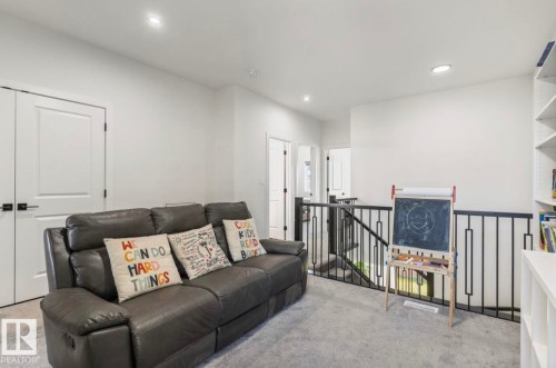 White walls, recessed lighting, white doors with matte black hardware, black metal railing, and built-in shelving - 19703 29 Avenue Nw, Edmonton, AB 