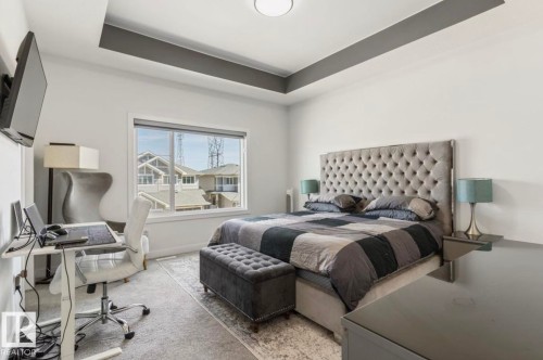 Recessed tray ceiling with accent molding, window featuring horizontal blinds, and wall-mounted television - 19703 29 Avenue Nw, Edmonton, AB 