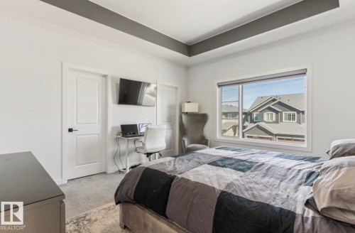 Tray ceiling with accent paint, expansive window, light gray carpeting, and white interior doors with black hardware - 19703 29 Avenue Nw, Edmonton, AB 