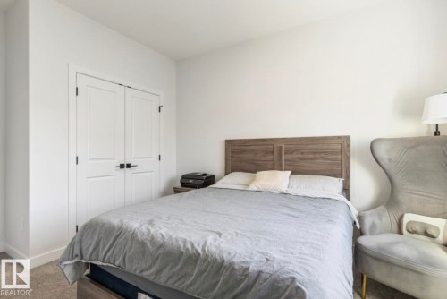 White walls, wood-finish headboard, built-in closet with panel doors, and carpet flooring - 19703 29 Avenue Nw, Edmonton, AB 
