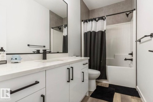White vanity with black hardware, integrated sink, and wall-mounted mirror - 19703 29 Avenue Nw, Edmonton, AB 
