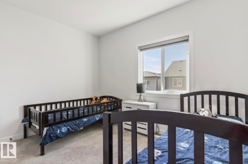 Spacious room featuring light gray walls, plush carpeting, a large window, and a built-in window treatment - 19703 29 Avenue Nw, Edmonton, AB 