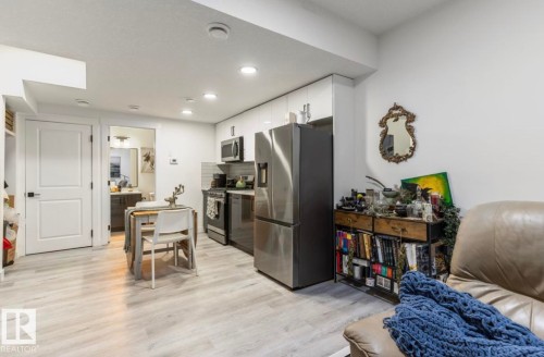 Galley kitchen with stainless steel appliances, white cabinetry, and recessed lighting - 19703 29 Avenue Nw, Edmonton, AB 
