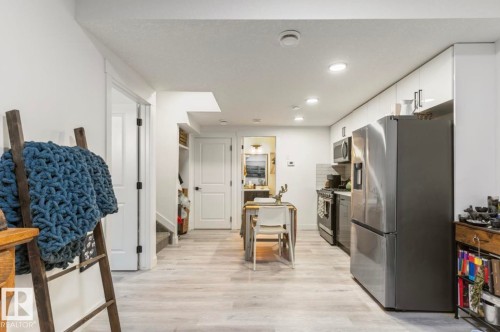 Integrated kitchen space featuring stainless steel appliances, light wood-finish flooring, recessed lighting, white cabinetry, and a subway tile backsplash - 19703 29 Avenue Nw, Edmonton, AB 