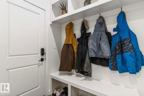 Built-in mudroom storage featuring bench seating, upper shelving, and coat hooks - 19703 29 Avenue Nw, Edmonton, AB 