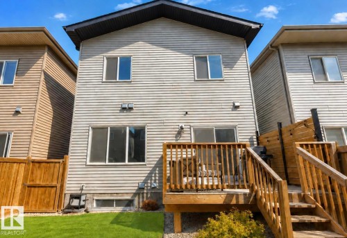 Rear exterior with horizontal siding, a wooden deck, and a manicured lawn - 19703 29 Avenue Nw, Edmonton, AB 
