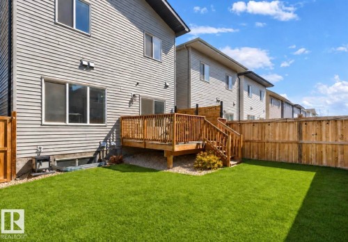 Expansive backyard featuring a wood deck with stairs, a privacy fence, and a green lawn - 19703 29 Avenue Nw, Edmonton, AB 