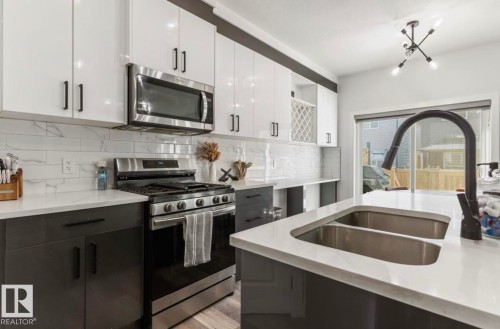 Modern kitchen featuring white upper cabinetry, dark lower cabinetry, and light-toned countertops - 19703 29 Avenue Nw, Edmonton, AB 