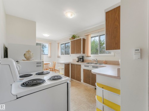 Kitchen featuring a double basin sink, tile flooring, and multiple windows providing natural illumination - 12614 69 Street Nw, Edmonton, AB 