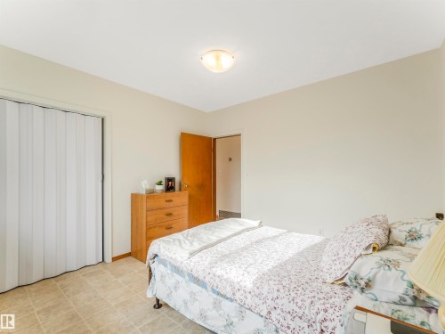 Textured accordion closet door, neutral wall tones, semi-flush ceiling light fixture, wood-finish interior door, tiled flooring - 12614 69 Street Nw, Edmonton, AB 