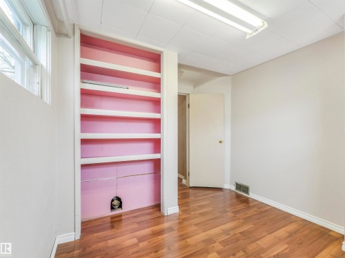 Wood-finish flooring, built-in shelving, white trim, and a drop ceiling with fluorescent lighting - 12614 69 Street Nw, Edmonton, AB 
