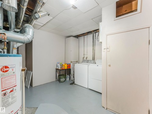 Utility area featuring a water heater, laundry appliances, and exposed overhead ductwork - 12614 69 Street Nw, Edmonton, AB 